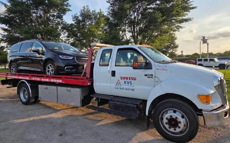 KVS Prime Services flatbed with a black Chrysler Pacifica loaded on the deck