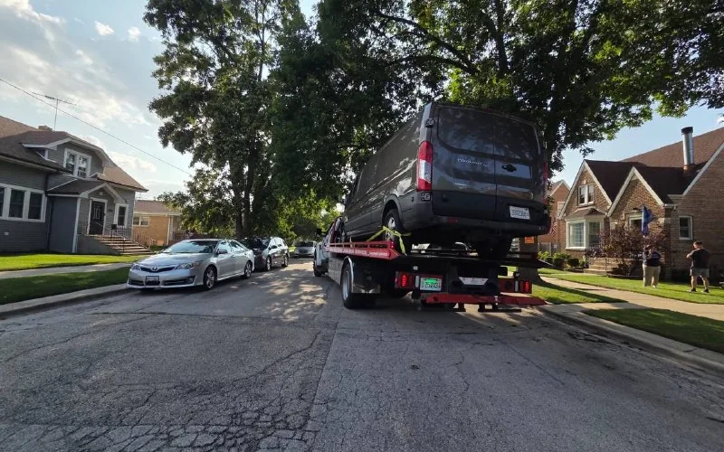 Ford Transit van loaded on the KVS flatbed on a residential Chicago street
