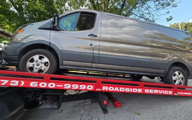 Ford Transit cargo van loaded on the KVS flatbed, deck rail lettered with the dispatch number